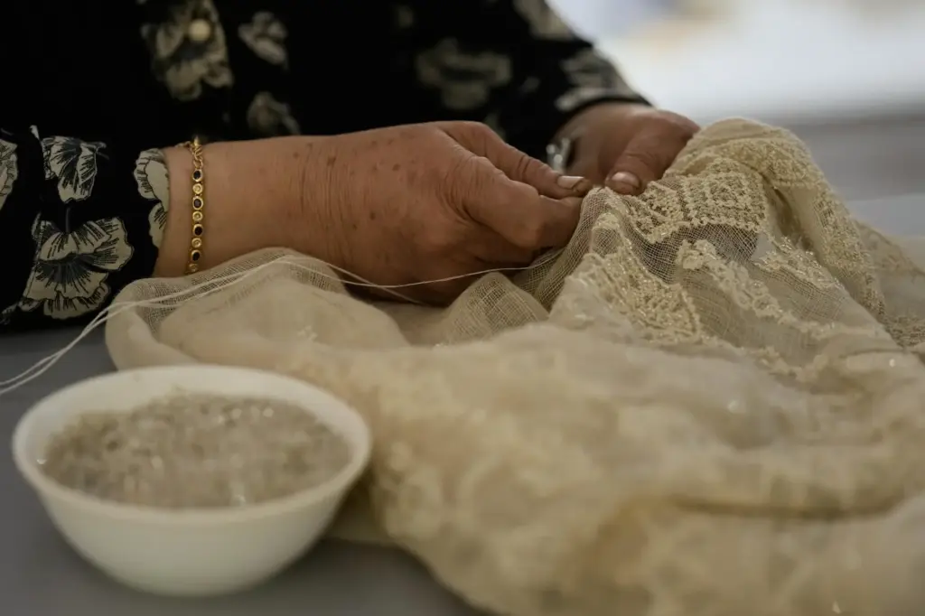 Palestinian weaver Samira Nasser works on a handmade embroidered piece...