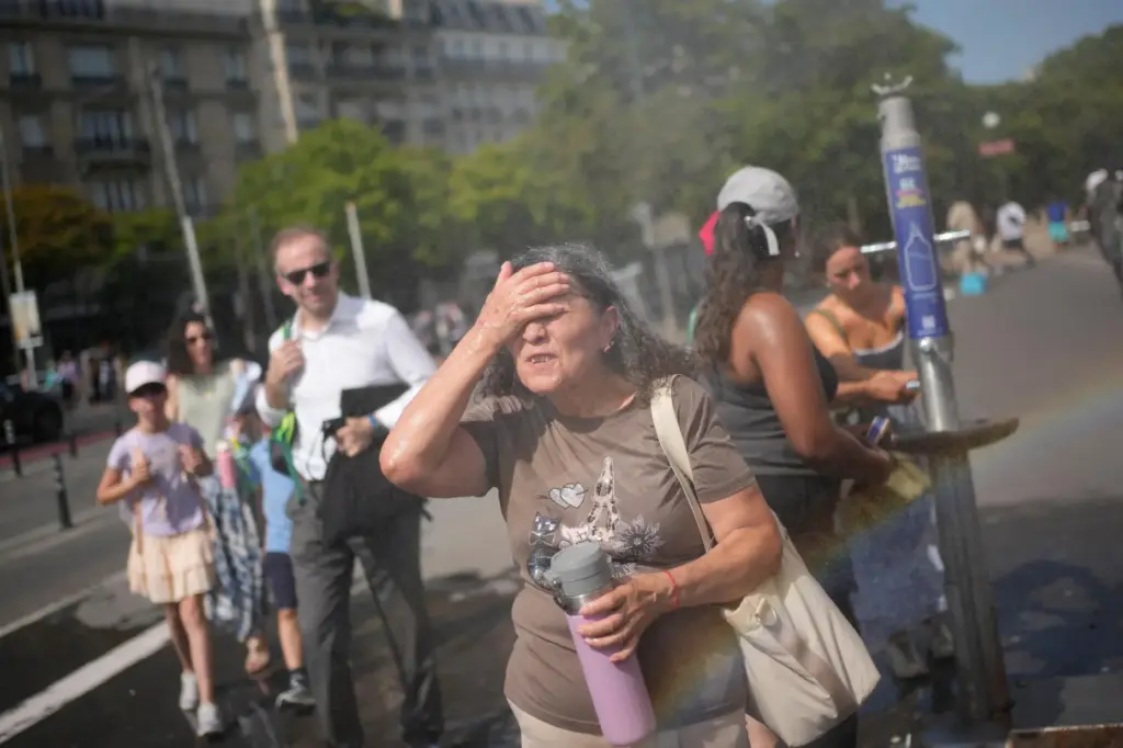 Tourists cool off at a public water fountain In Paris.