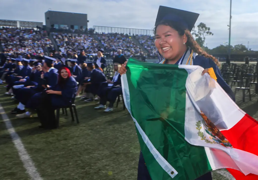 Nicole Gomez carries the Mexican Flag as she graduates from...