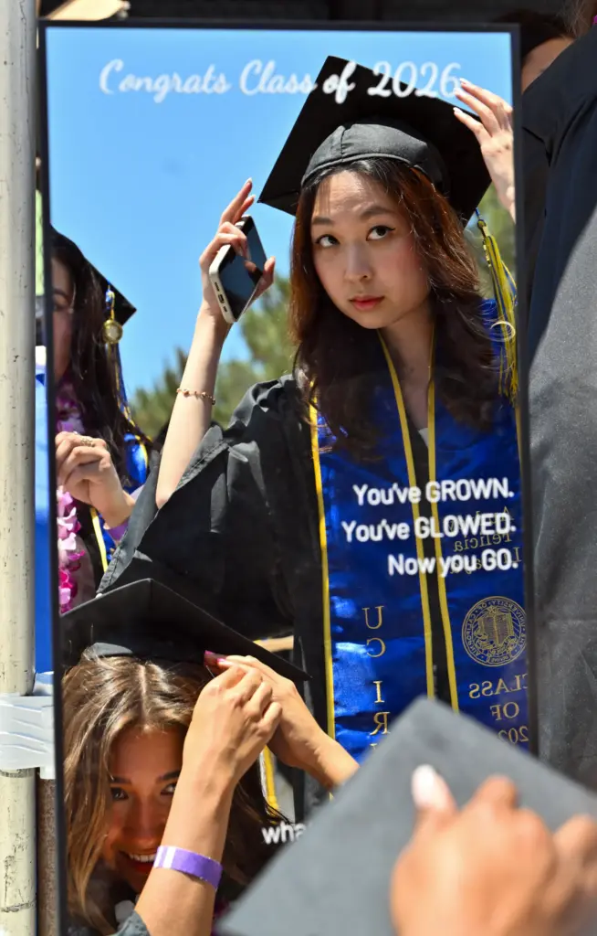 Graduates Audrey Liujaya, top, and Grace Kalmbach use a mirror...