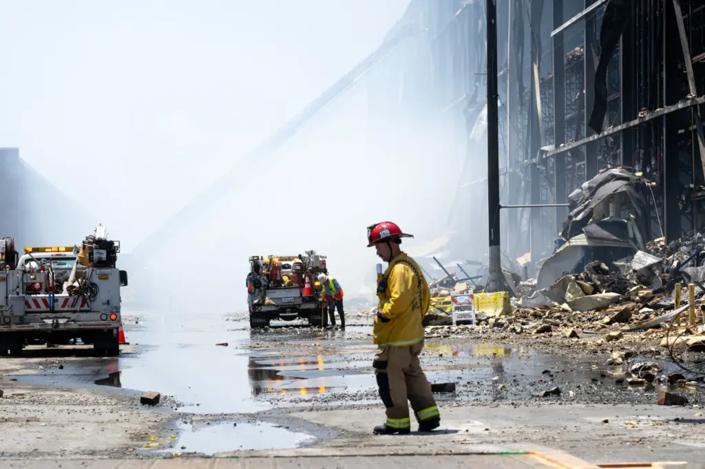 Firefighters use a high-powered water canon from Texes to douse...