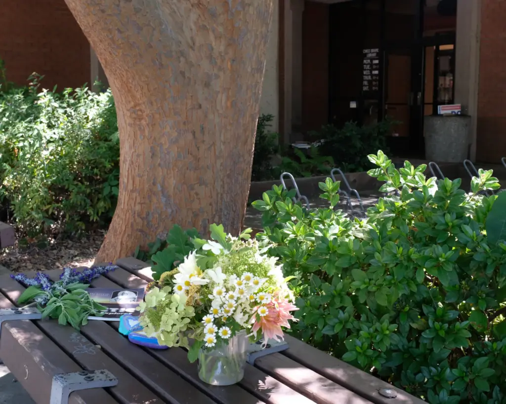 Flowers are placed on a bench outside the front entrance...