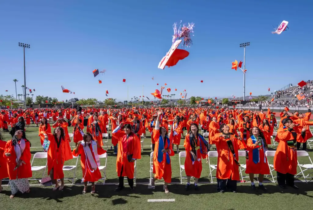Orange High School graduates toss their caps in the air...
