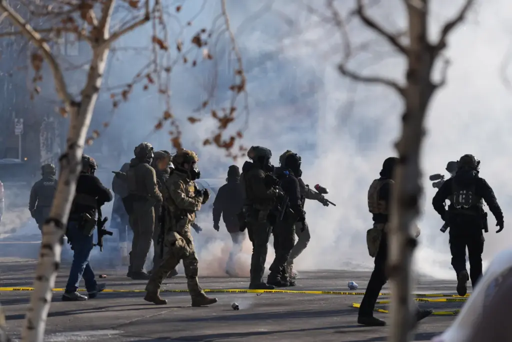 FILE – Federal immigration officers deploy tear gas at protesters...
