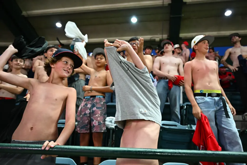 A fan, front right, takes off his shirt to join...
