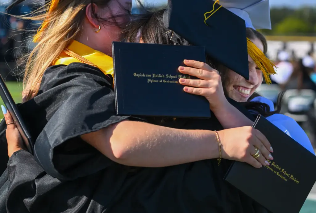 Graduate Maya Aoude, center, hugs classmates Siena Lassegard and Hallie...