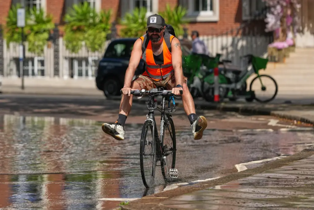 A man keeps his legs dry as he cycles through...