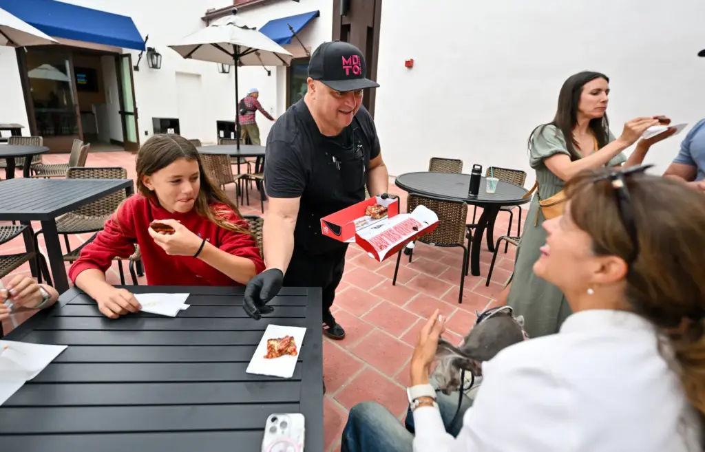 Lee Kindell, owner of Moto Pizza, hands out samples to...