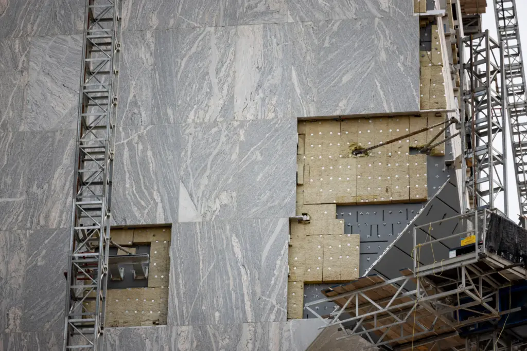 Granite panels are installed as construction continues on the tower...