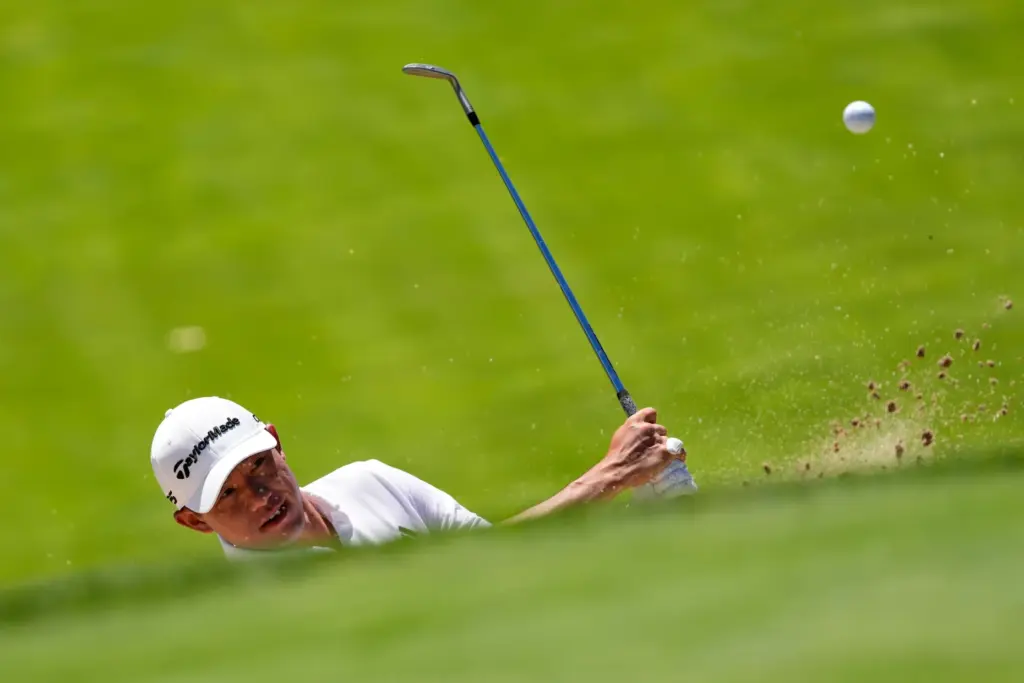 Collin Morikawa hits from the bunker on the 11th hole...