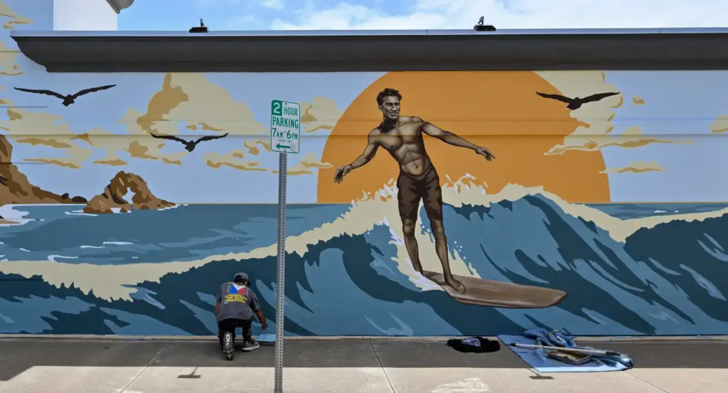Austin Gosswiller helps artist Jack Stricker, not pictured, put the...