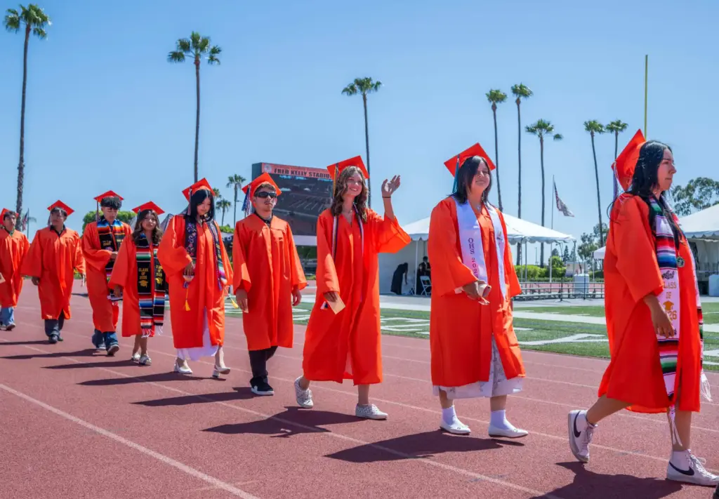 Graduates file into the stadium, acknowledging their loved ones in...