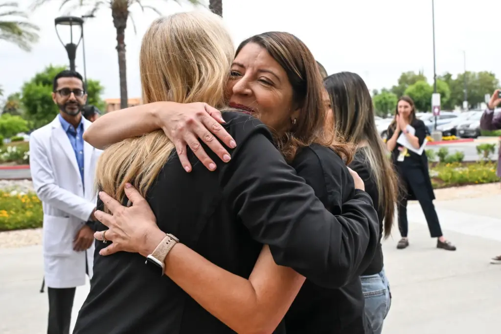 Leticia Rojas, right, wife of stroke survivor George Rojas, hugs...