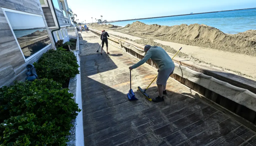 Ken Holt, and his wife, Gabriella Holt, clean up sand...