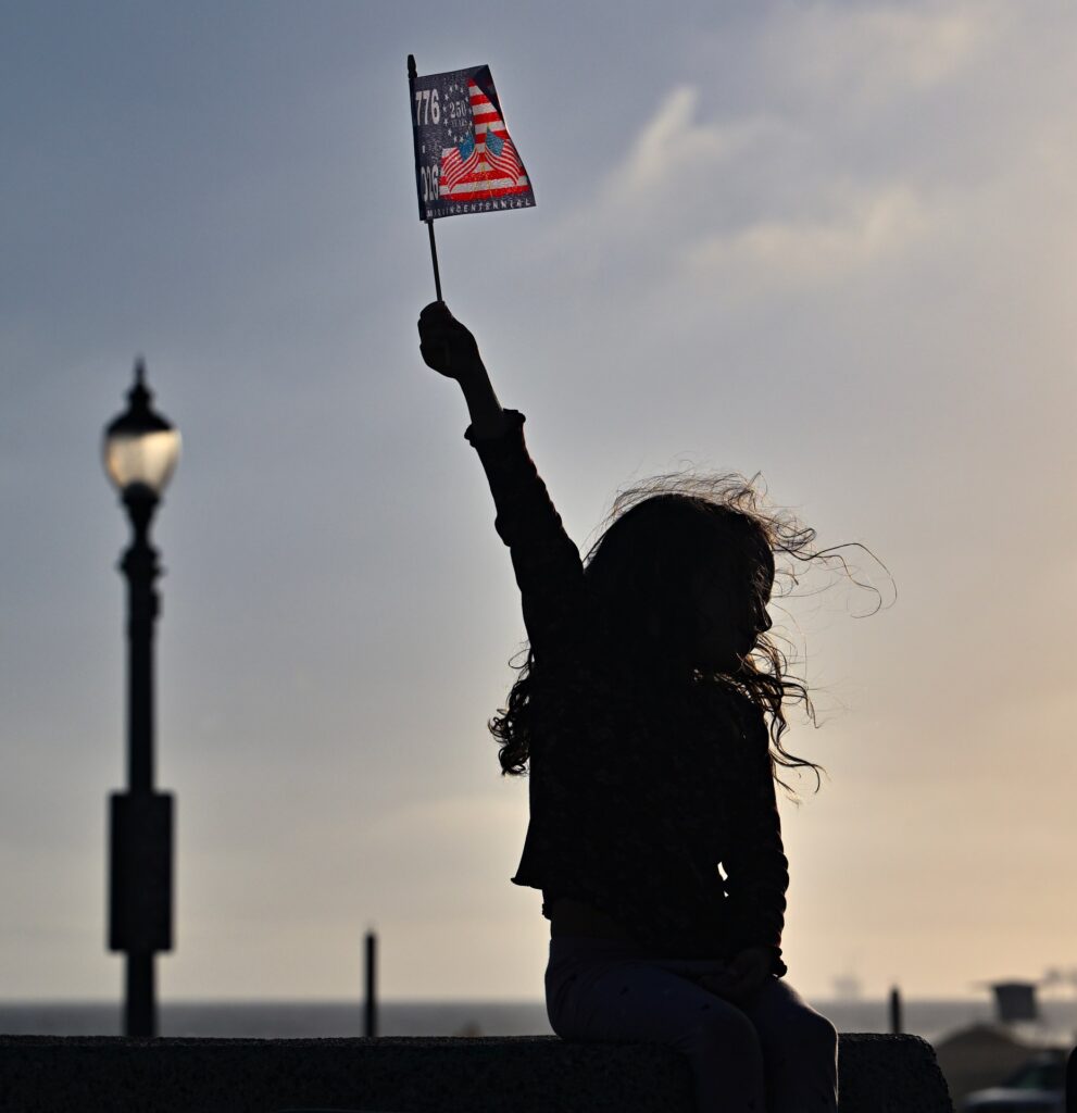 Rumi Fite, 5, waves an American semiquincentennial flag during a...