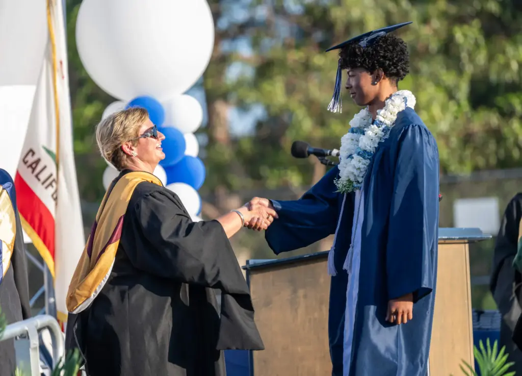 Markus Ashley shakes hands with Principal Alicia Foulk while walking...