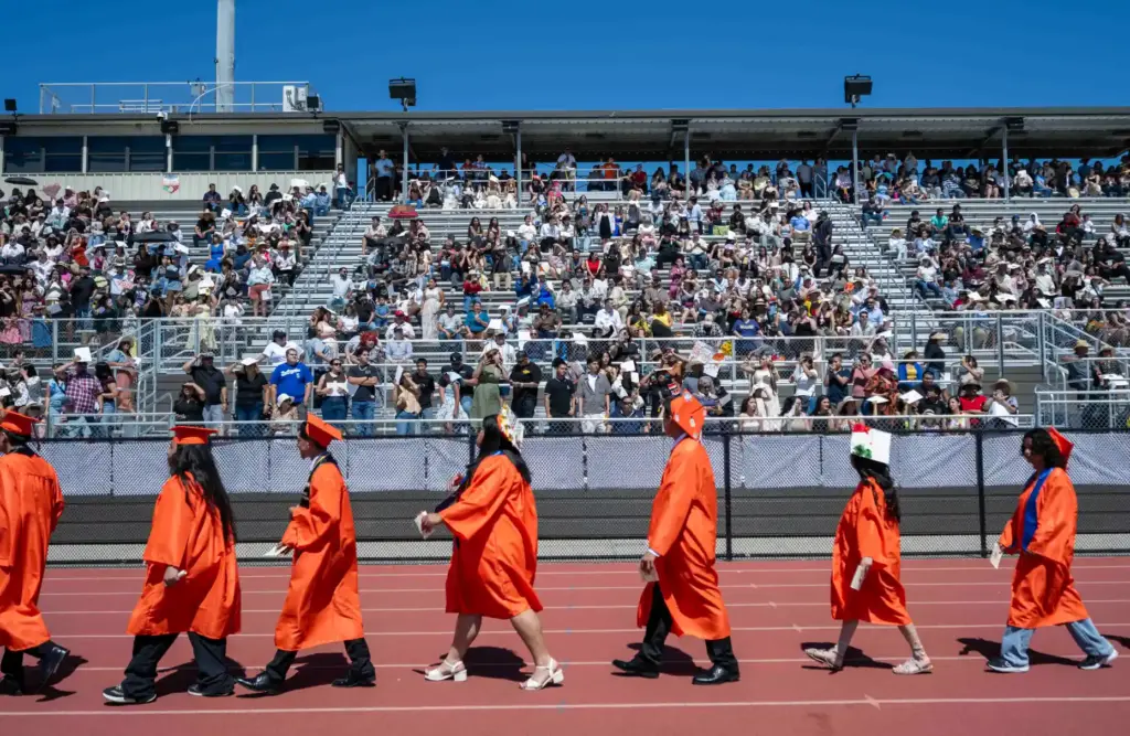 Graduates file into the stadium during the processional at Orange...