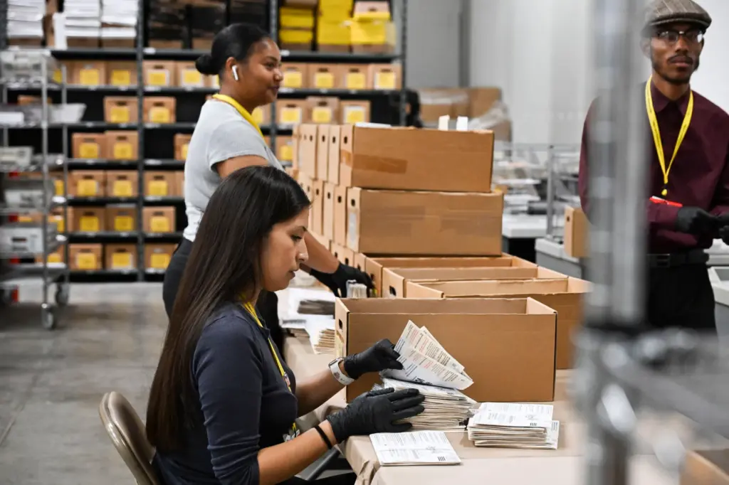 Temporary election assistants hand sort vote-by-mail ballots Monday, June 1,...