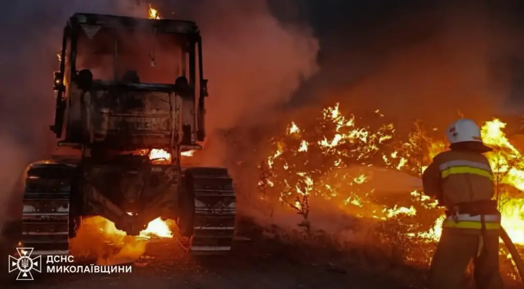 A rescue worker puts out a fire of a tractor destroyed by a Russian strike.
