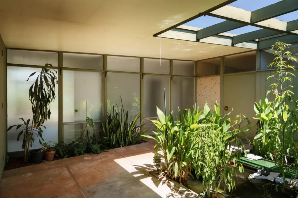 Roof beams form a grid above the fish pond in...