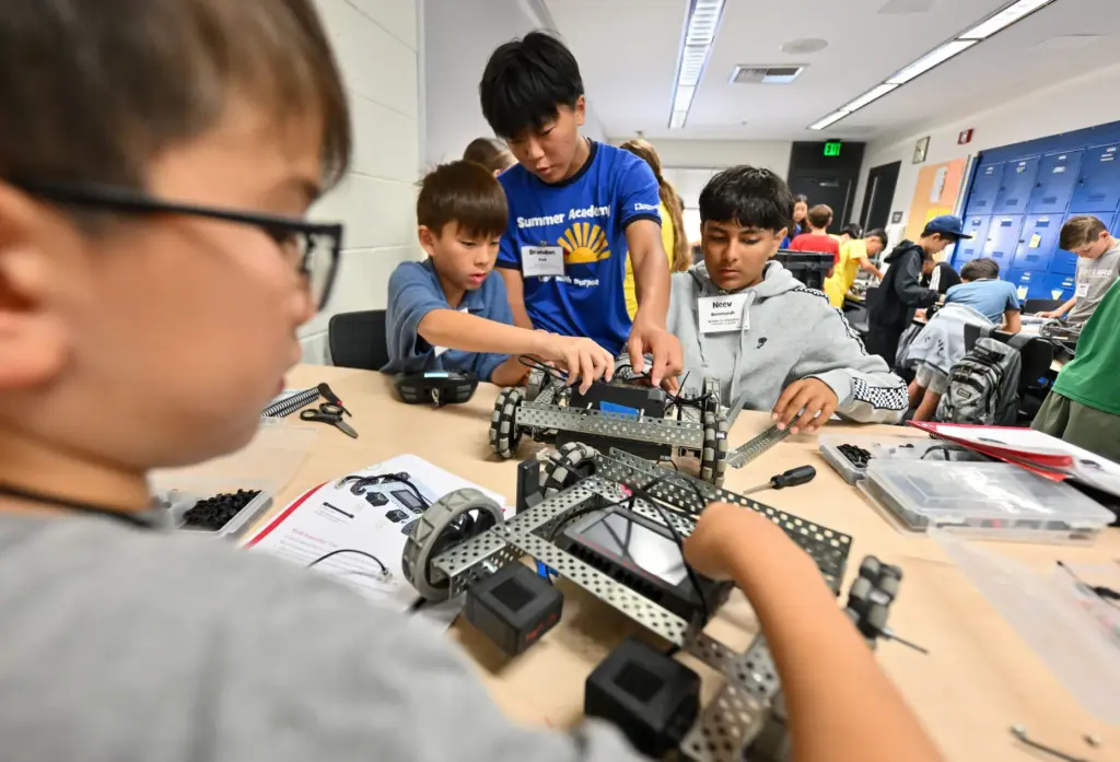 Intern Brandon Park, center, helps campers Aaron Blue and Neev...