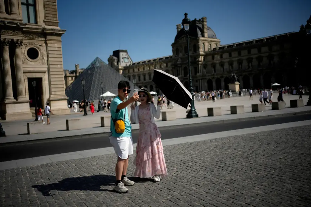 Tourists with an umbrella take a photo in Paris, as...