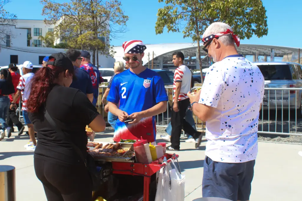 Team USA fans buying bacon-wrapped hot dogs from vendors outside...