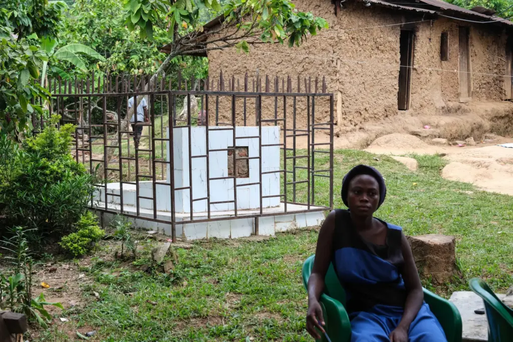 A woman sits beside a caged grave of a person who died from the first outbreak of Bundibugyo virus.