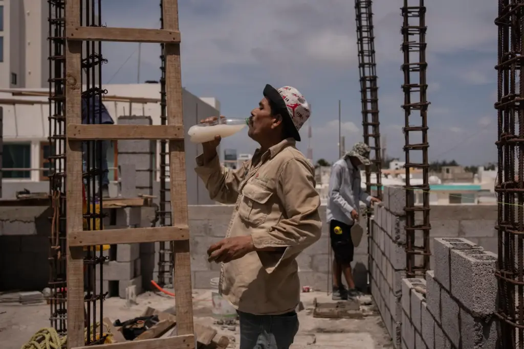 FILE – Jorge Moreno, a worker, drinks flavored water to...