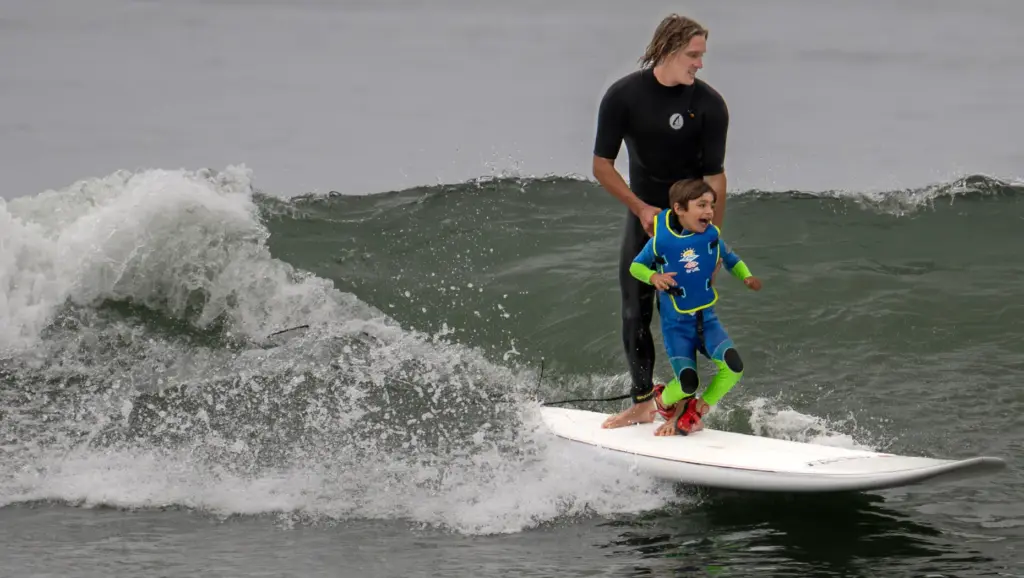 Surfers Healing volunteer Blake Michaels helps 5-year-old Luka Richey stay...