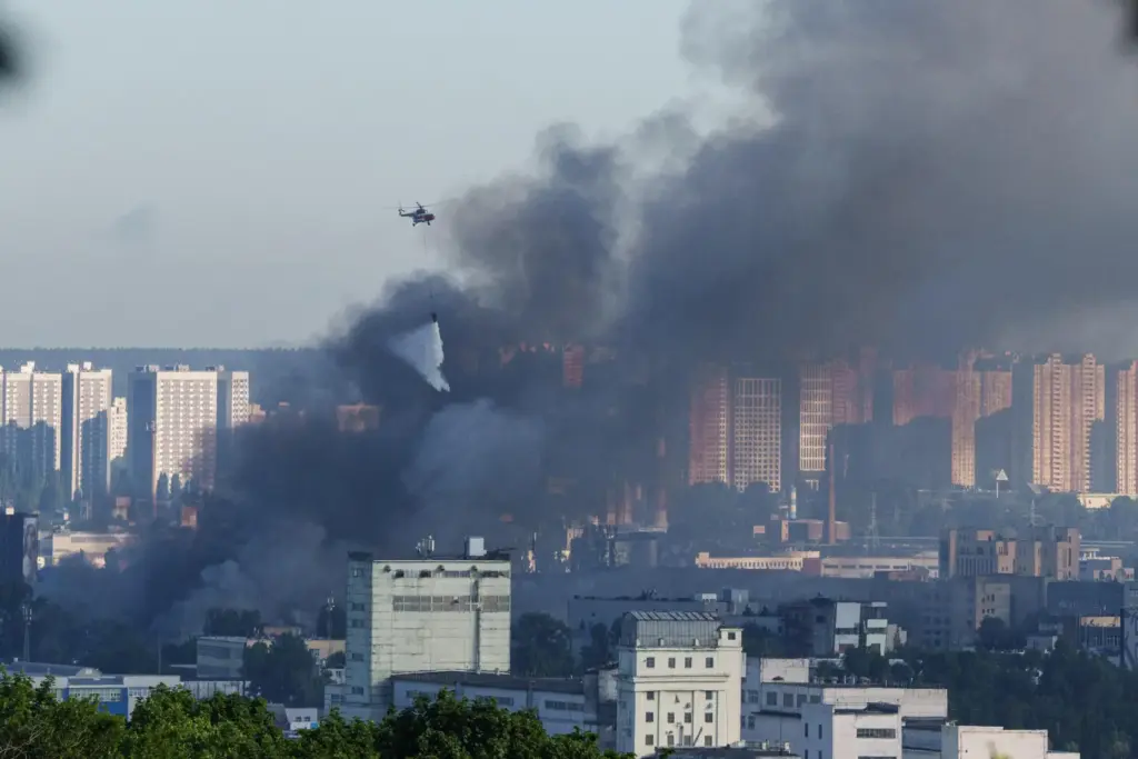 A helicopter drops water from a drop tank onto a fire at a market.