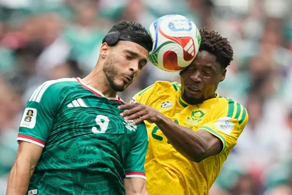 Mexico’s Raul Jimenez, left, jumps for the ball with South...