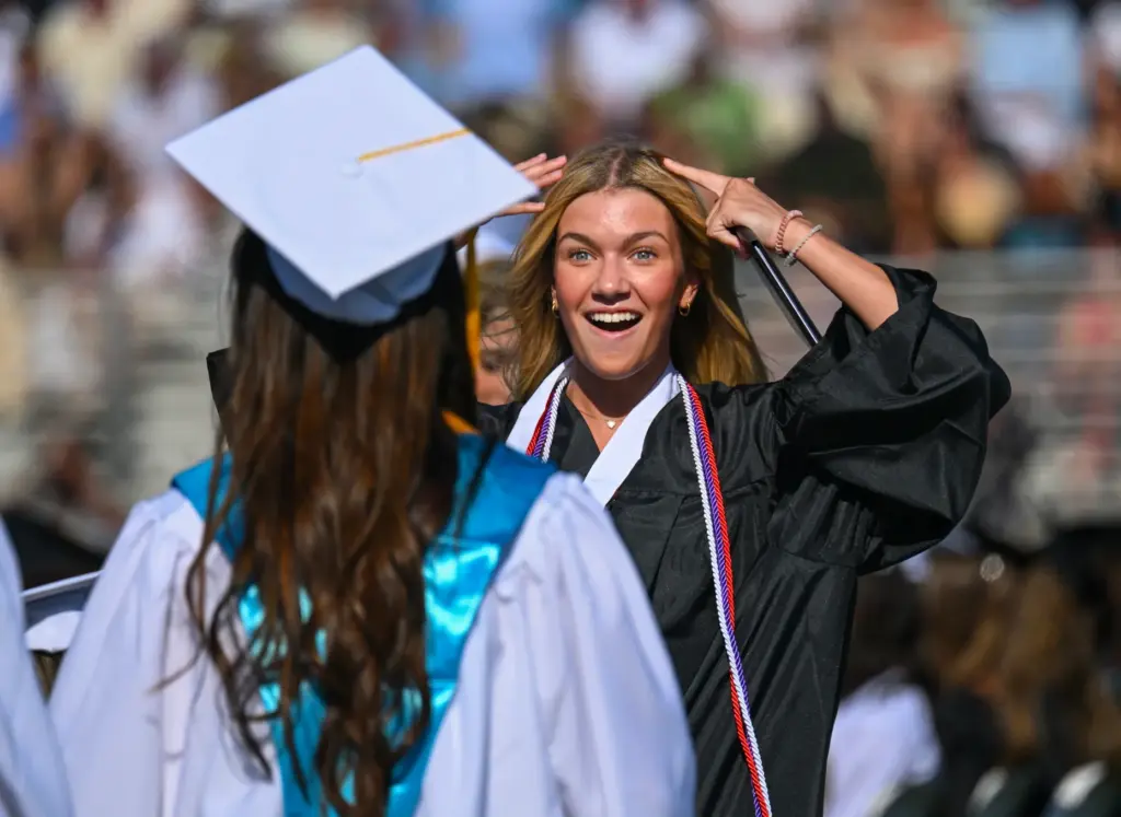 Graduate Liesl Merkh gestures to a friend that she lost...