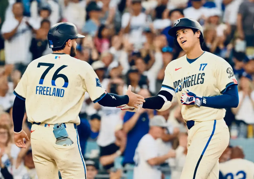 Shohei Ohtani #17 of the Dodgers high fives teammate Alex...
