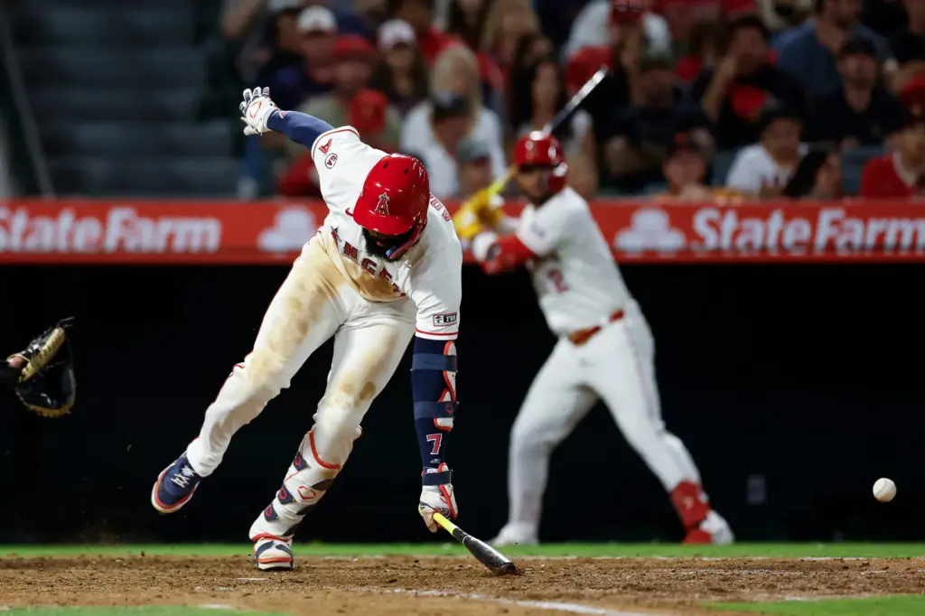 Angels’ Jo Adell (7) reacts after getting hit by a...
