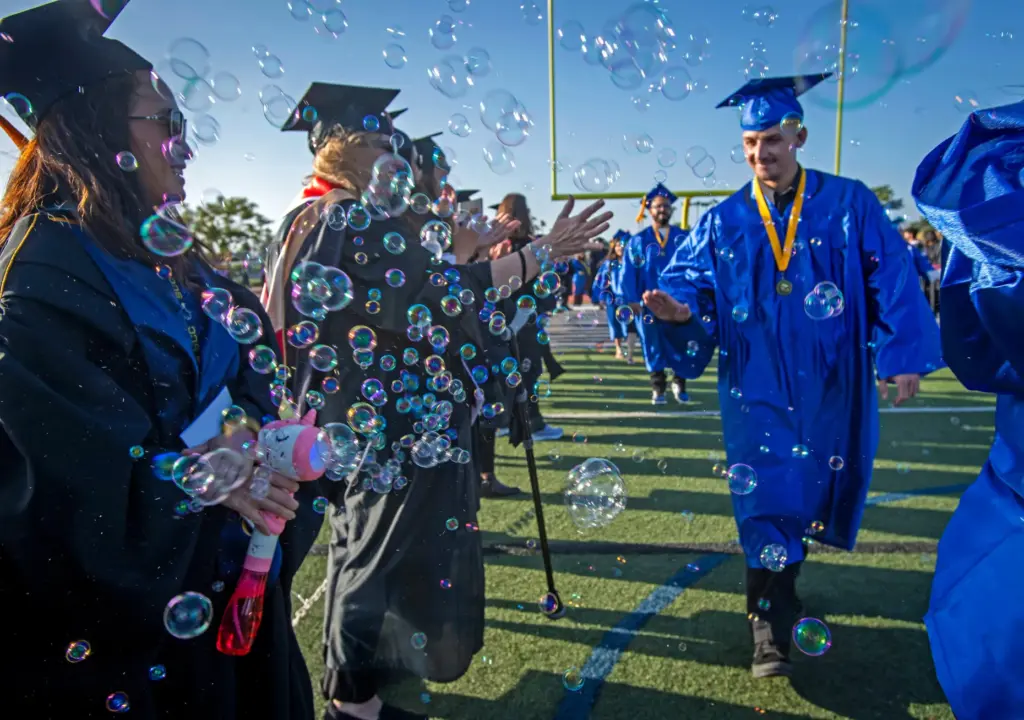 Graduates made their way through a cluster of bubbles provided...