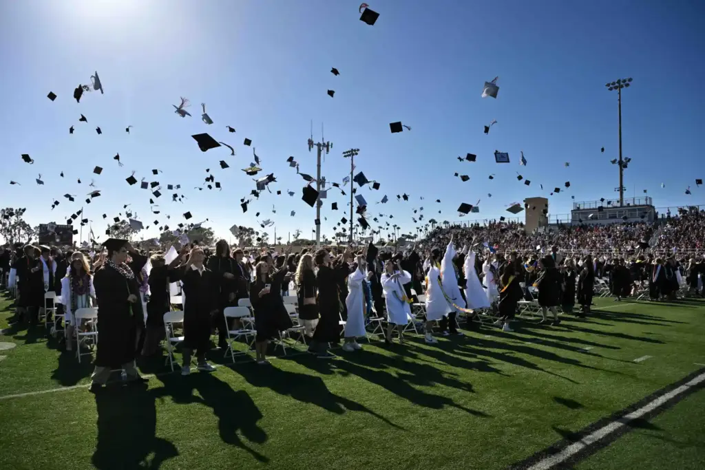 Graduates toss their caps into the air at the end...