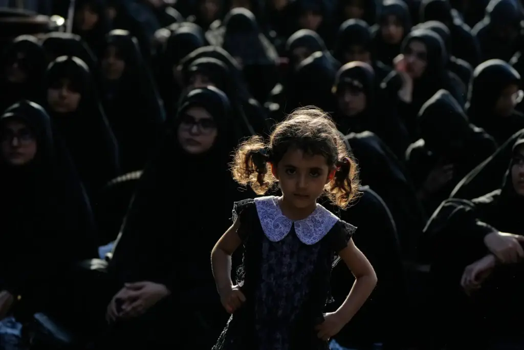 A girl looks on as women sit during a mourning ceremony in Tehran, Iran.