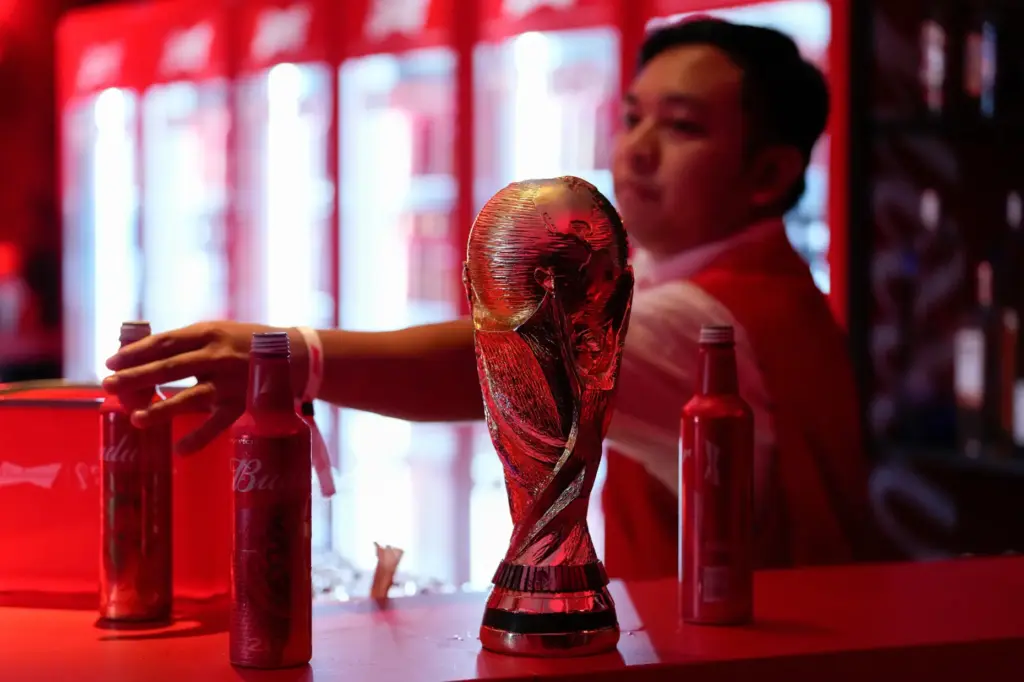 A bartender clears bottles of Budweiser beer from the bar.