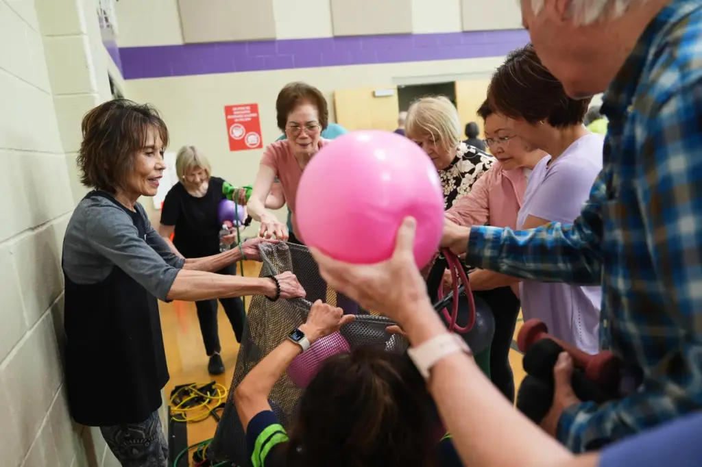 Instructor Bengie Santos, 72, collects small exercise balls.