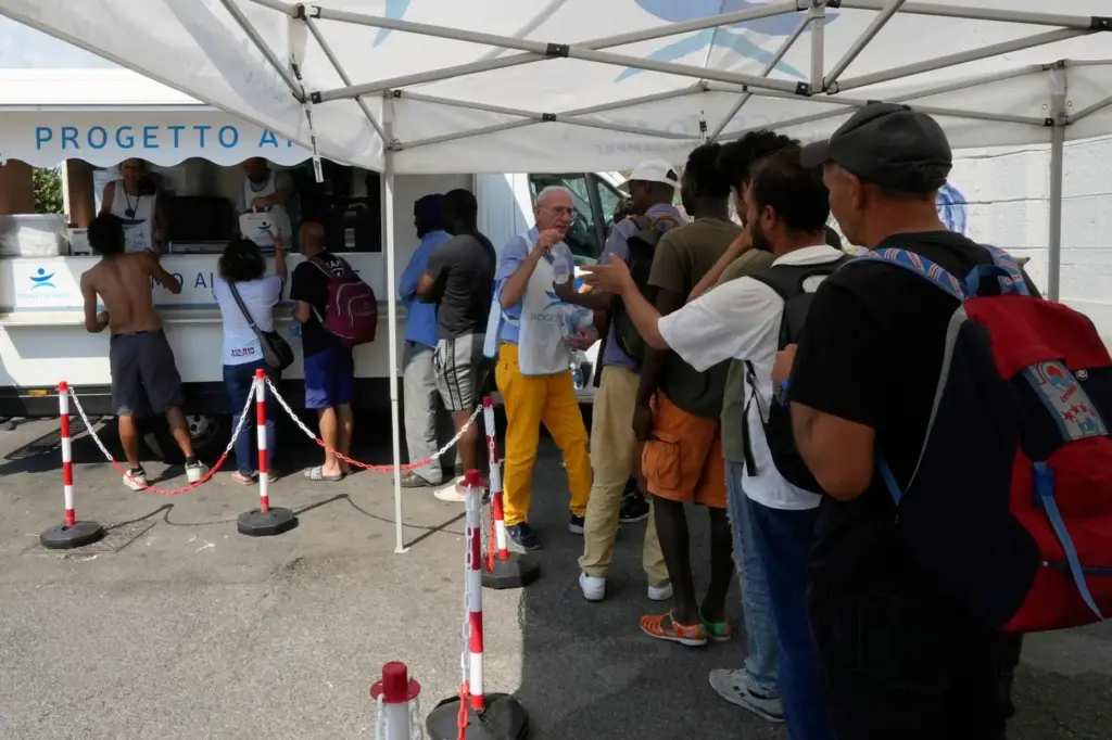 FILE – Volunteers distribute food and water to homeless people...