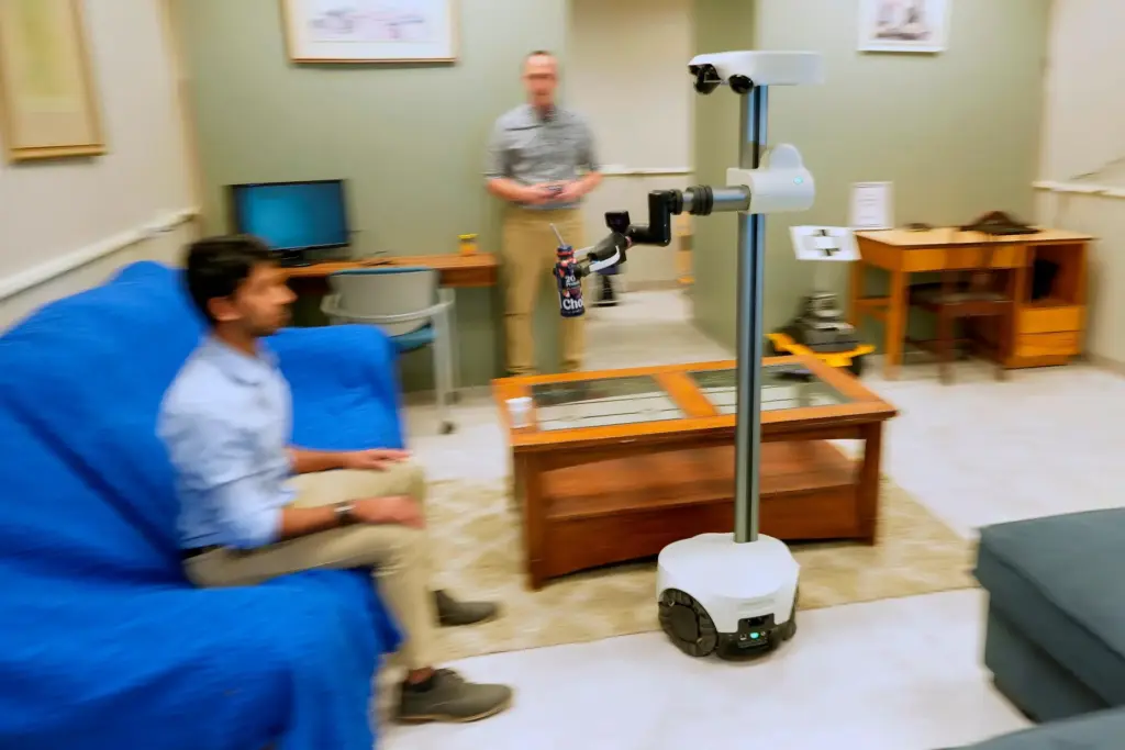 A robot operated by a robotics engineer brings a drink to colleague.