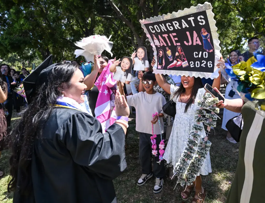 Graduate Janelle Calma, left, is greeted by friends and family...