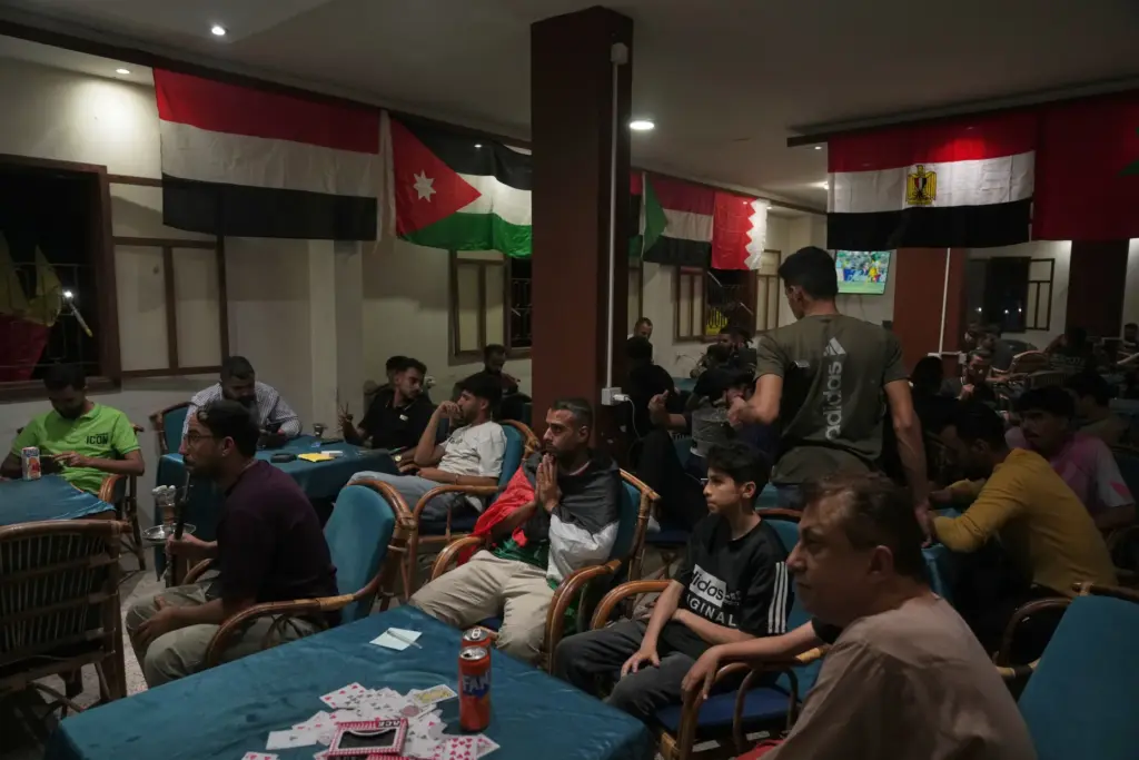 Soccer fans watch a broadcast of the opening match of...