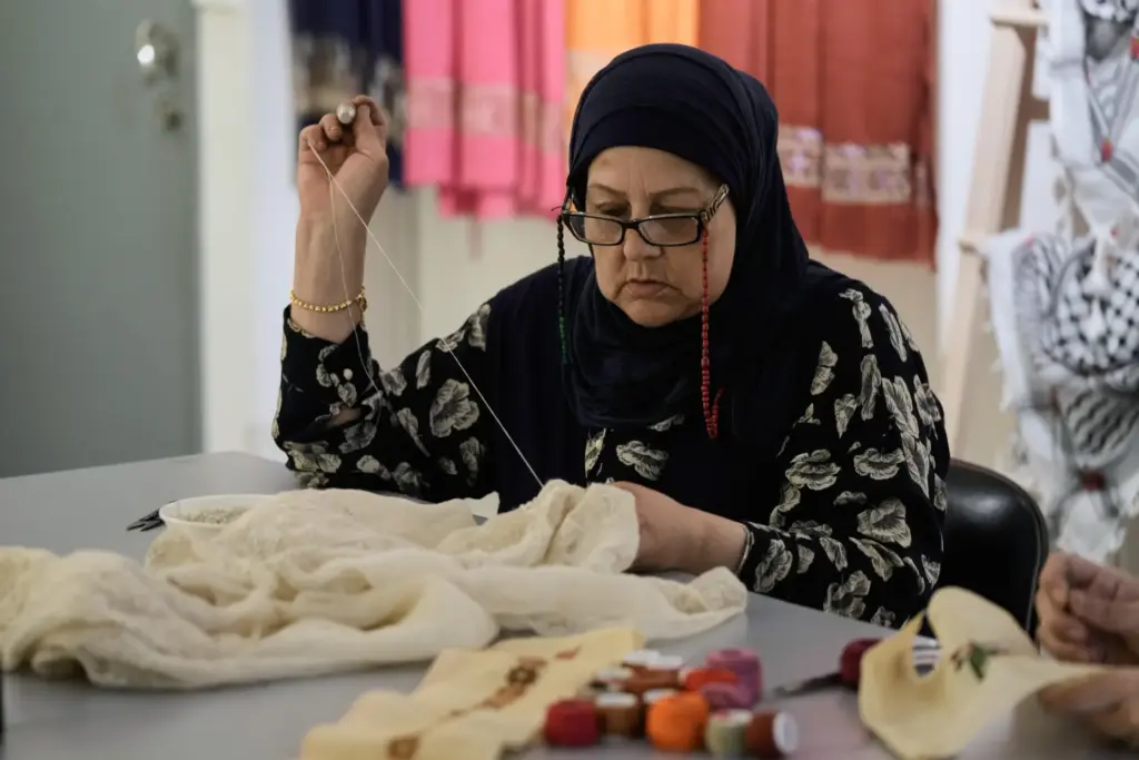 Palestinian weaver Samira Nasser works on a handmade embroidered piece...