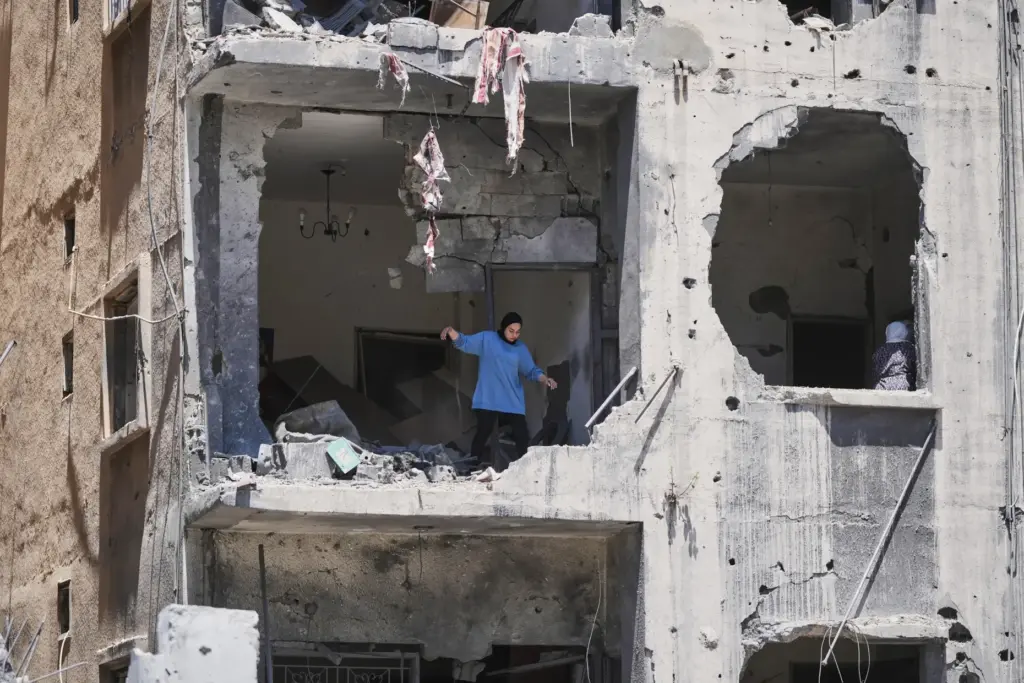 A woman walks through her apartment damaged in Israeli strikes...