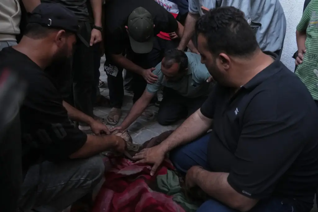Residents gather by the body of a killed Palestinian man following an Israeli airstrike.