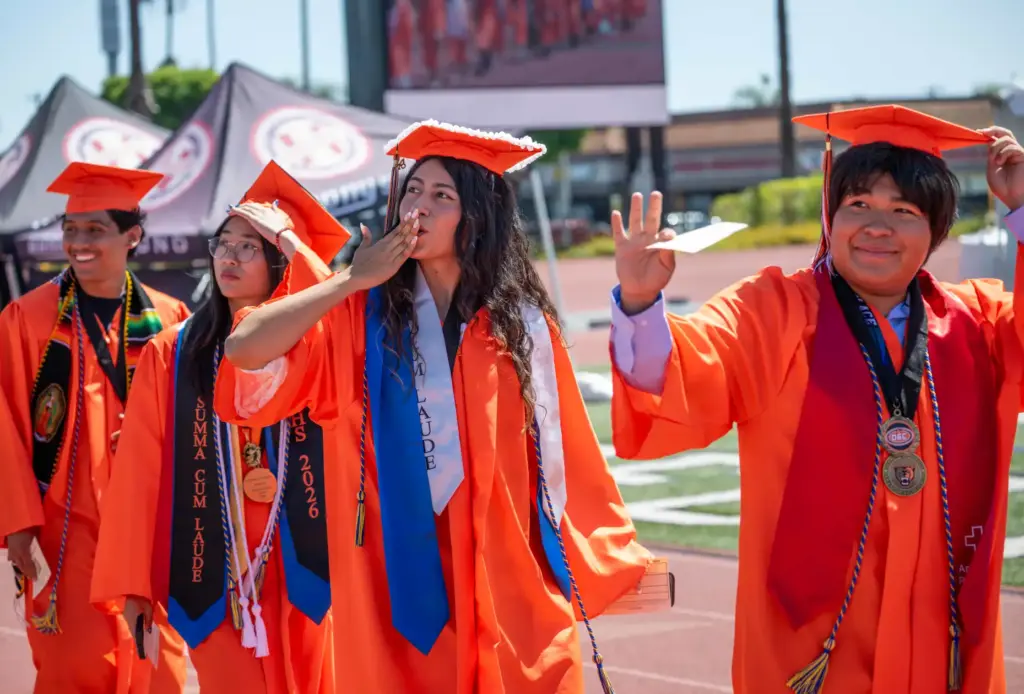 Graduates file into the stadium, acknowledging their loved ones in...