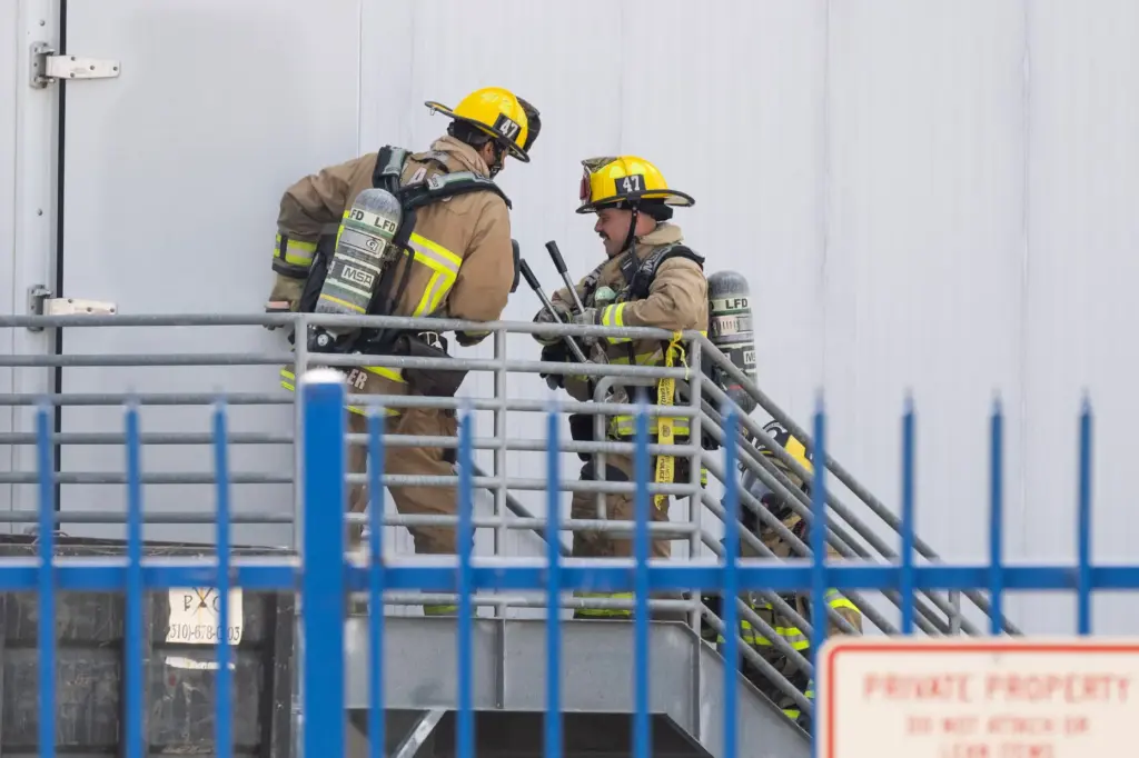 Firefighters enter the Lineage Logistics warehouse, a cold storage facility,...