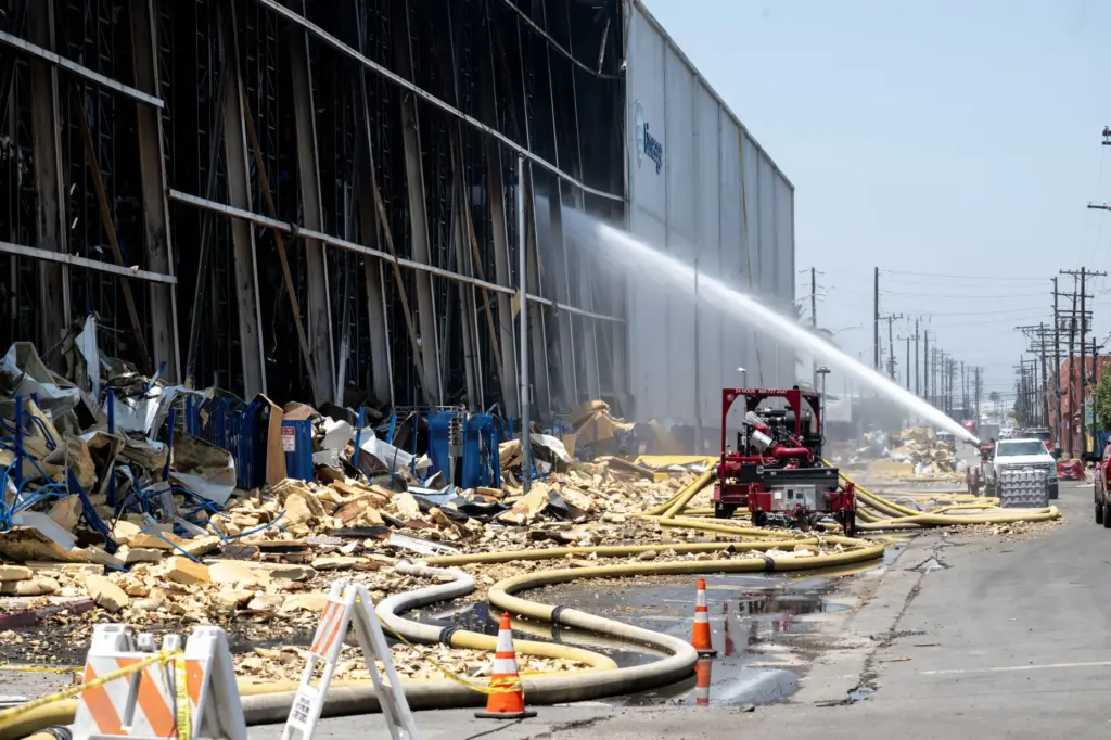 Firefighters use a high-powered water canon from Texes to douse...